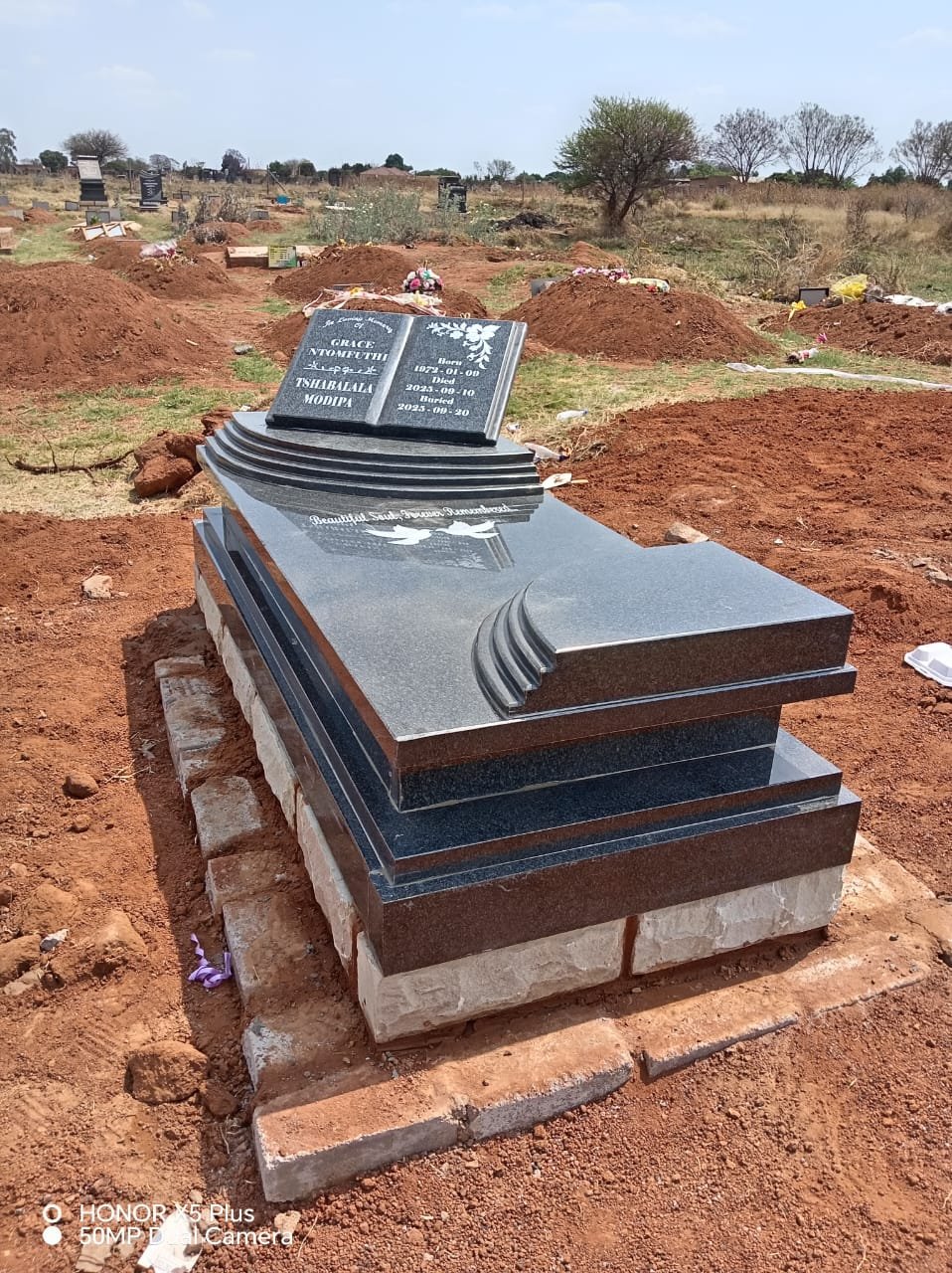 Polished black granite tombstone with tiered base